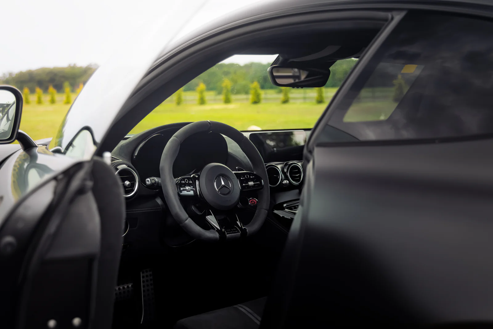 Open door framing the Mercedes-AMG cockpit and steering wheel