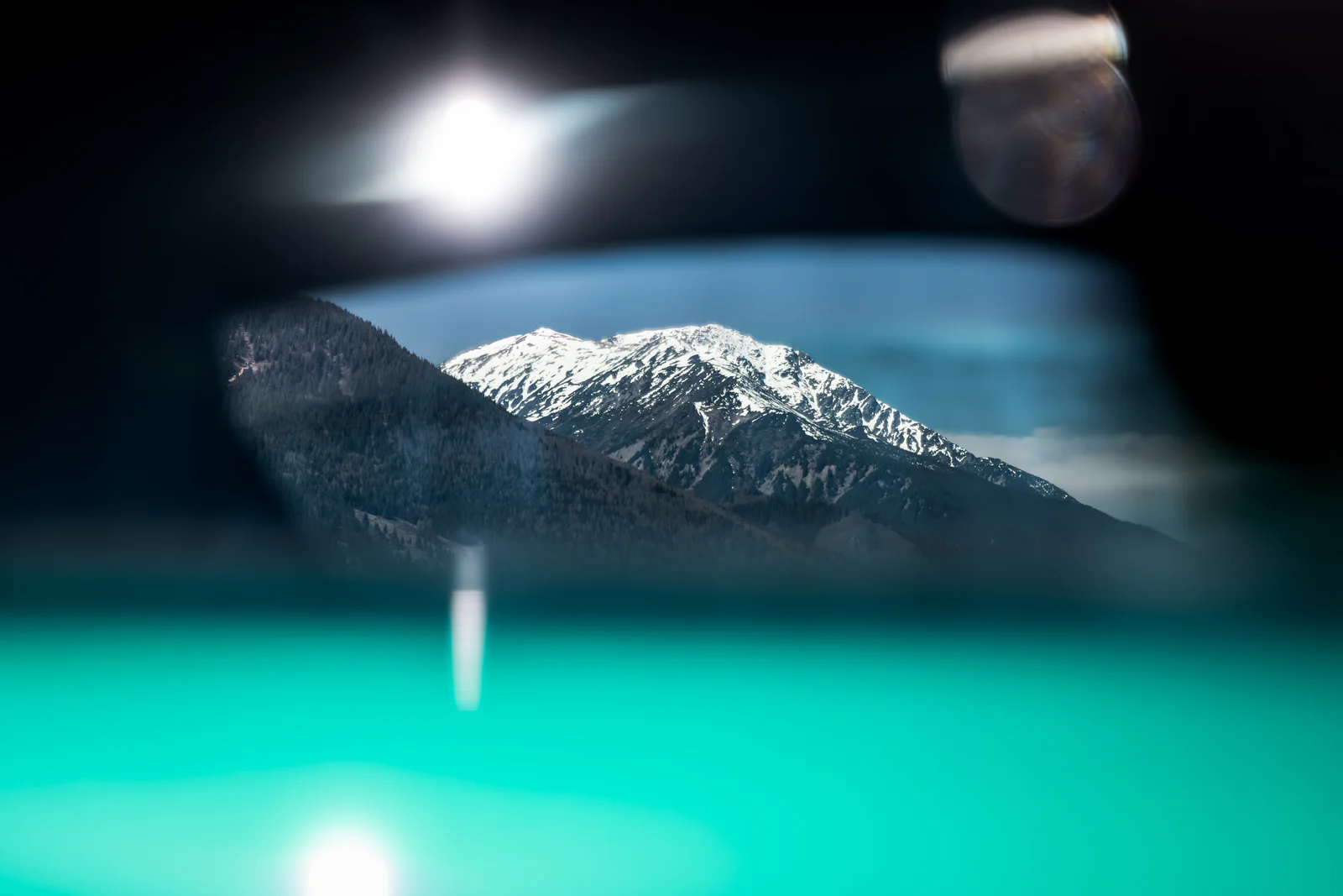 Snow-covered mountain reflected in the Aston Martin side mirror