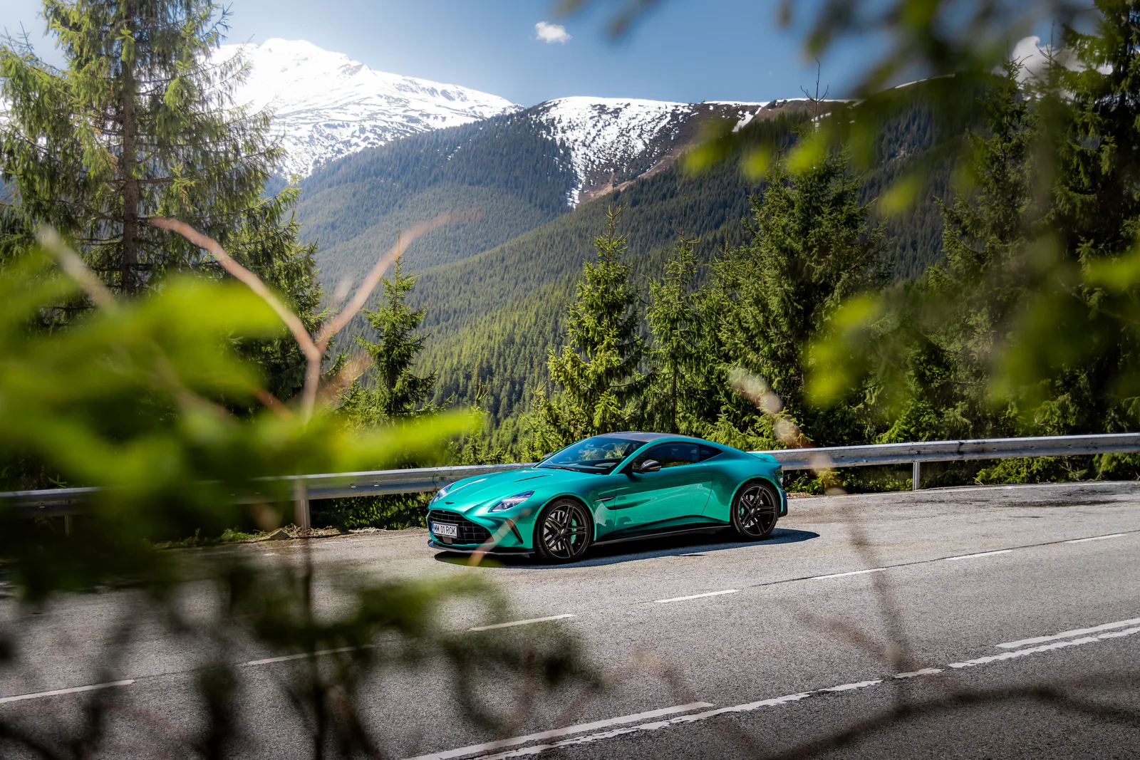 Front three-quarter view of the Vantage framed by foliage against a mountain landscape