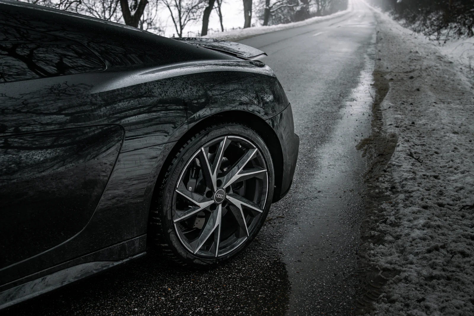 Rear wheel and glossy side body alongside the snow-lined road