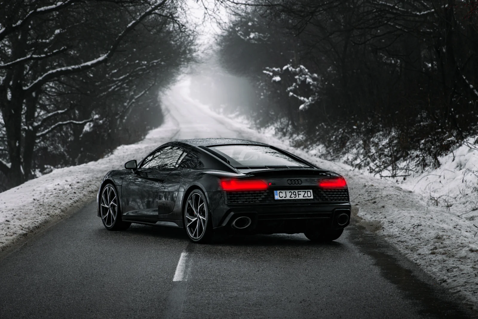 Rear three-quarter view of the R8 with red taillights in winter fog