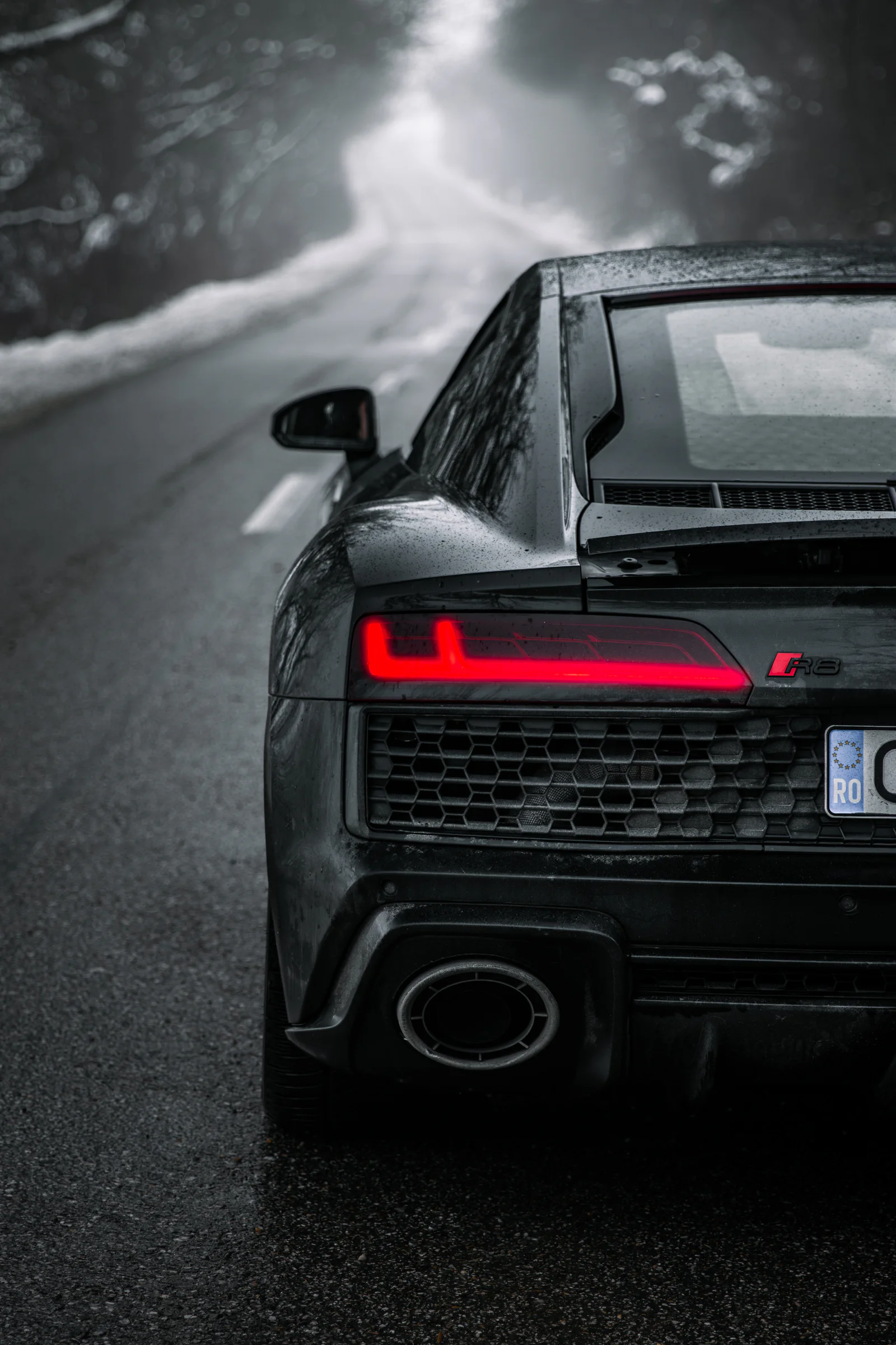 Red taillight, R8 badge and exhaust beside the misty road