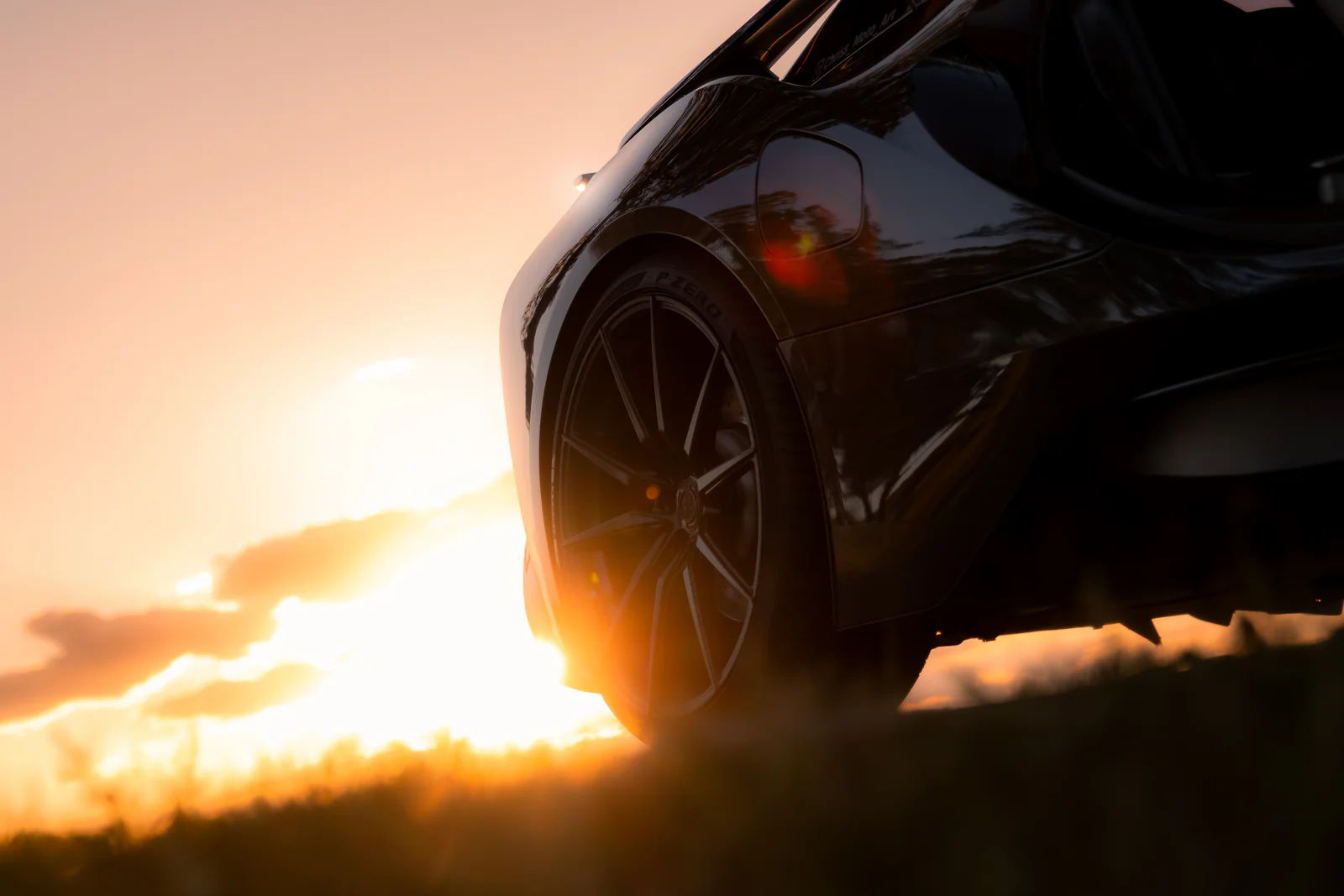 Low rear wheel and sculpted body silhouette beside the setting sun