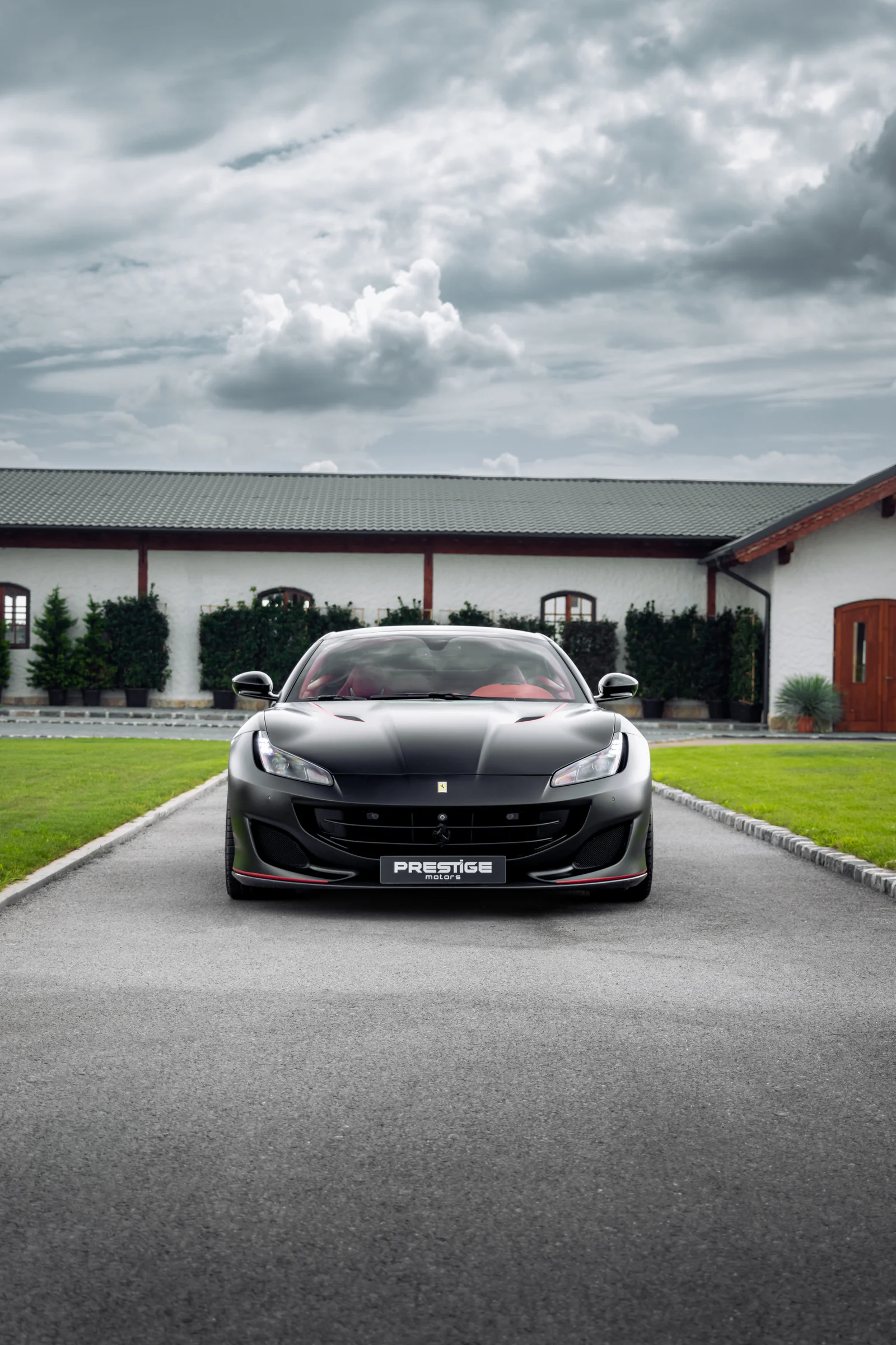 Matte black Ferrari Portofino viewed head-on beneath a cloudy sky