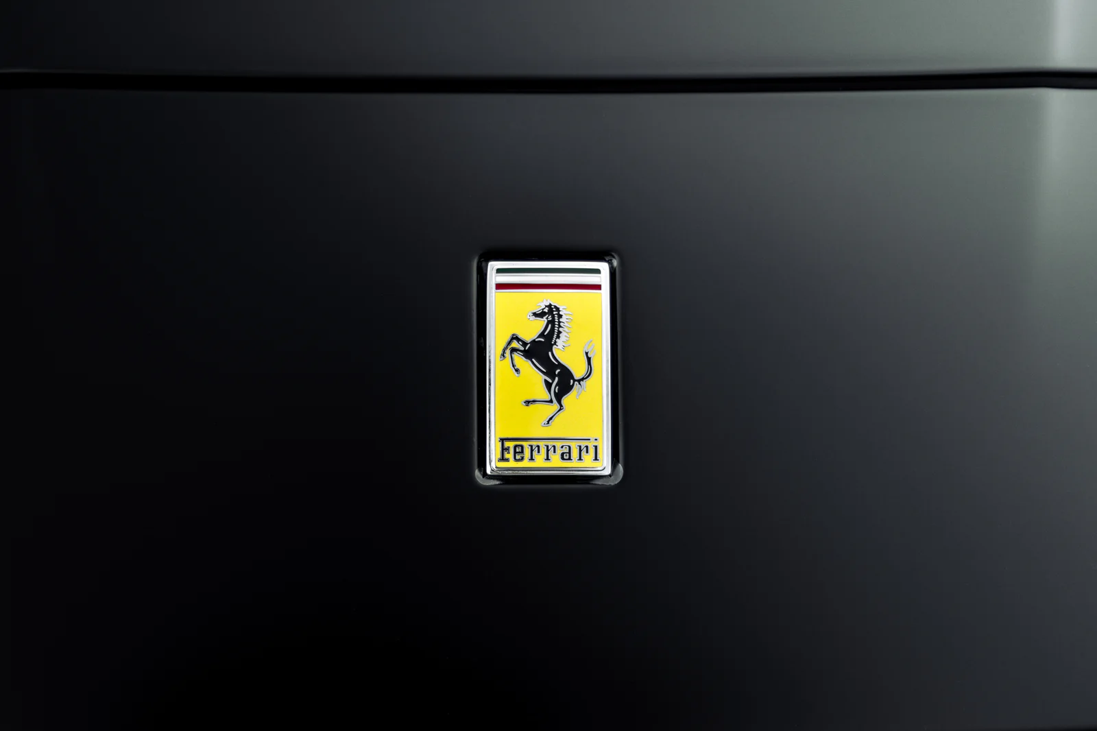 Yellow Ferrari bonnet badge on matte black paint