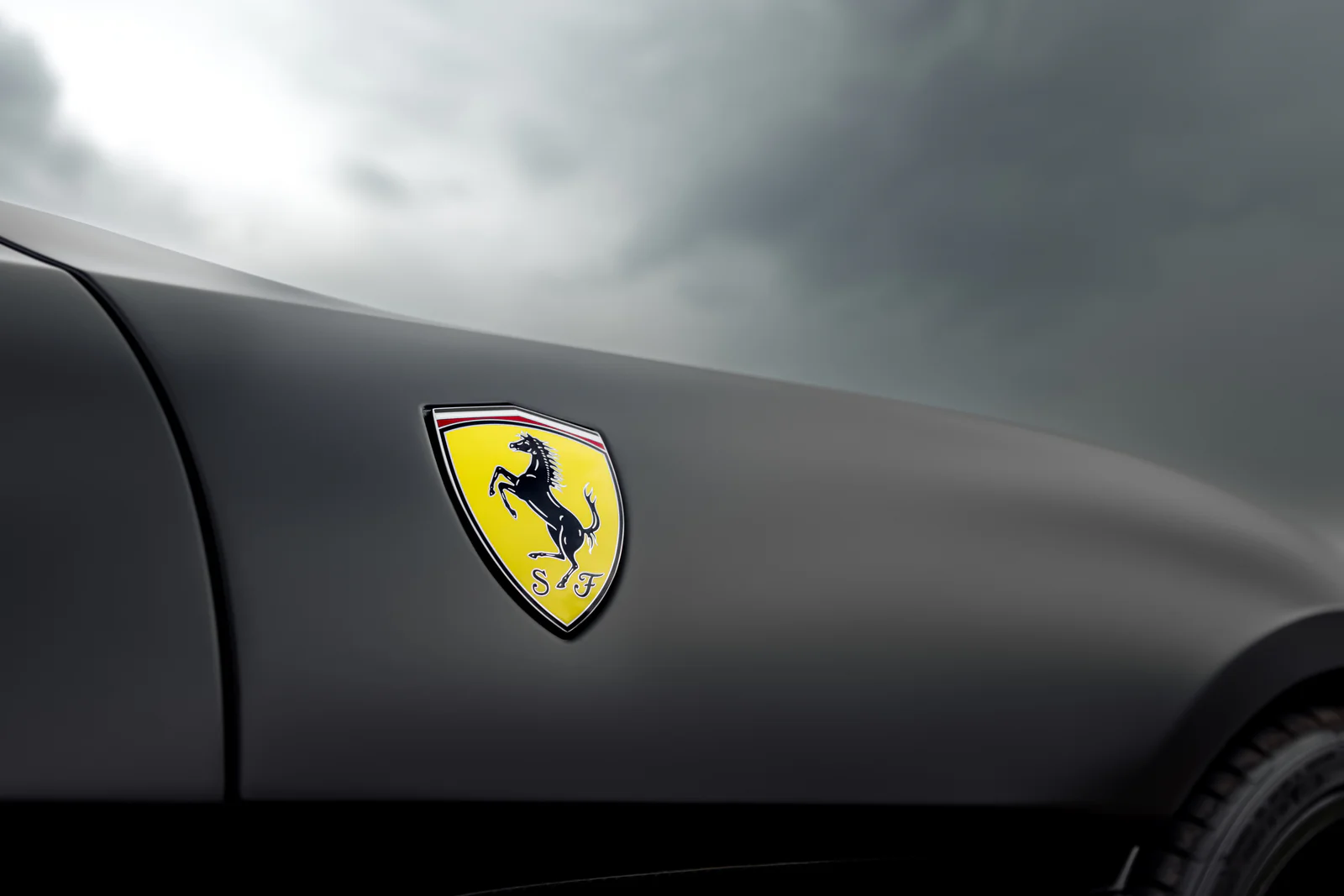 Ferrari shield badge on the sculpted front wing beneath a cloudy sky