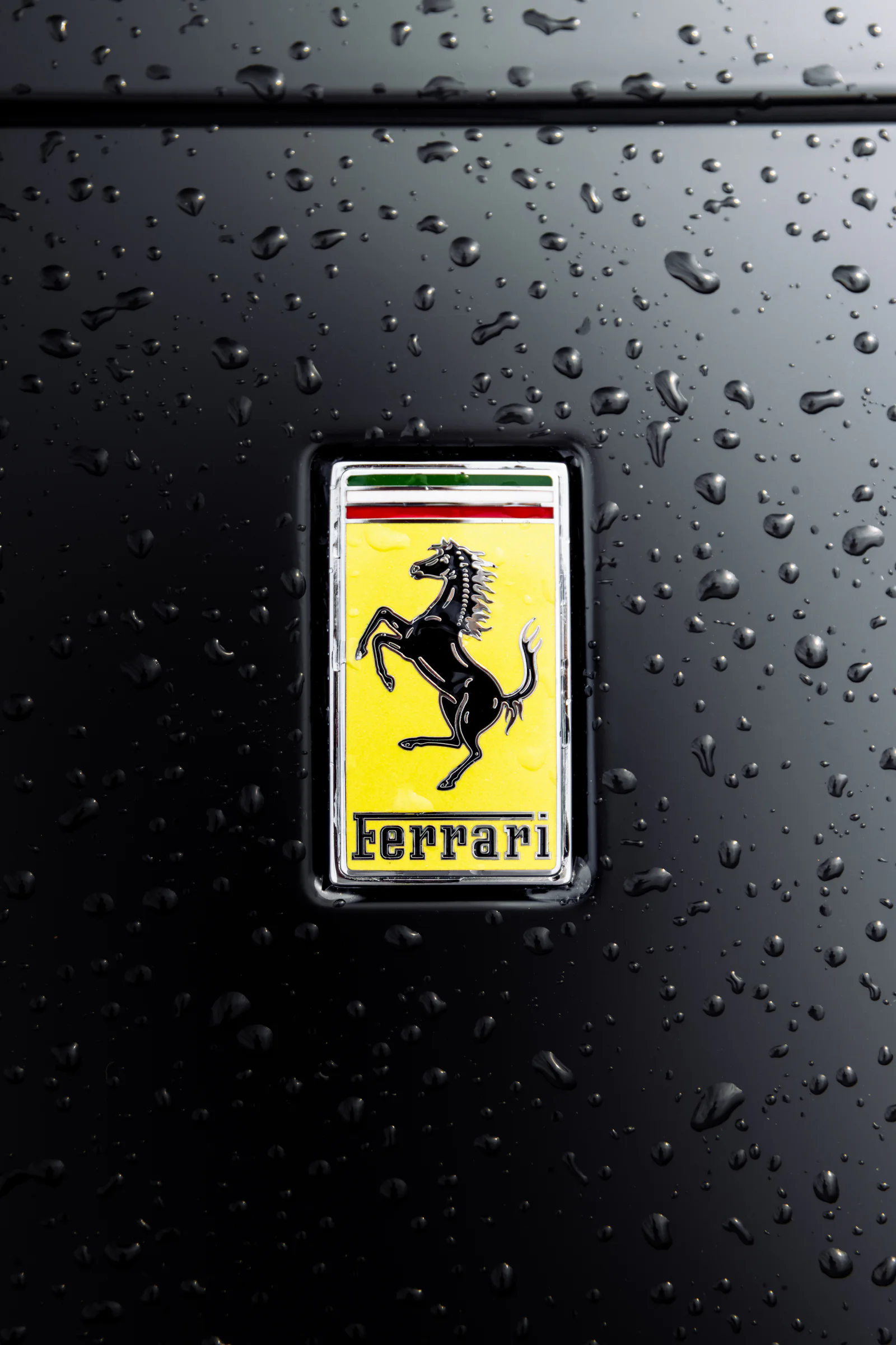 Rain droplets surrounding the yellow Ferrari bonnet badge