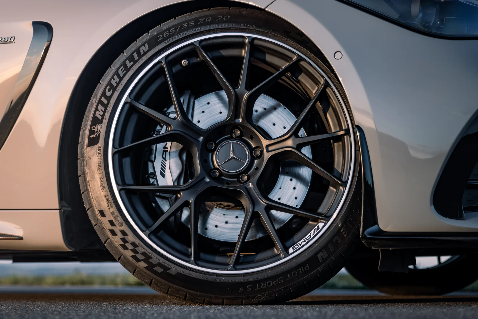 Black AMG alloy wheel and silver brake caliper in evening light