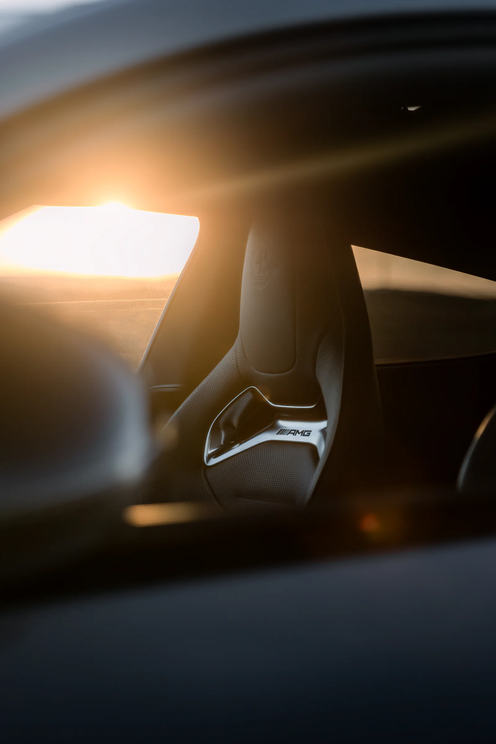 AMG performance seat framed through the window in golden sunlight