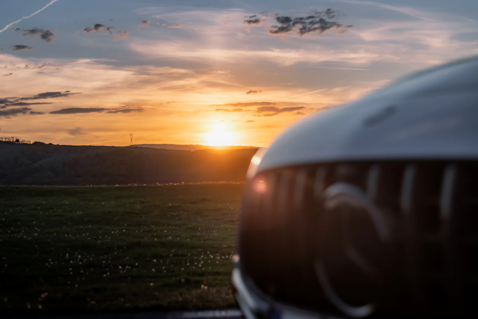 Sunset over the hills with the softly focused AMG grille in the foreground
