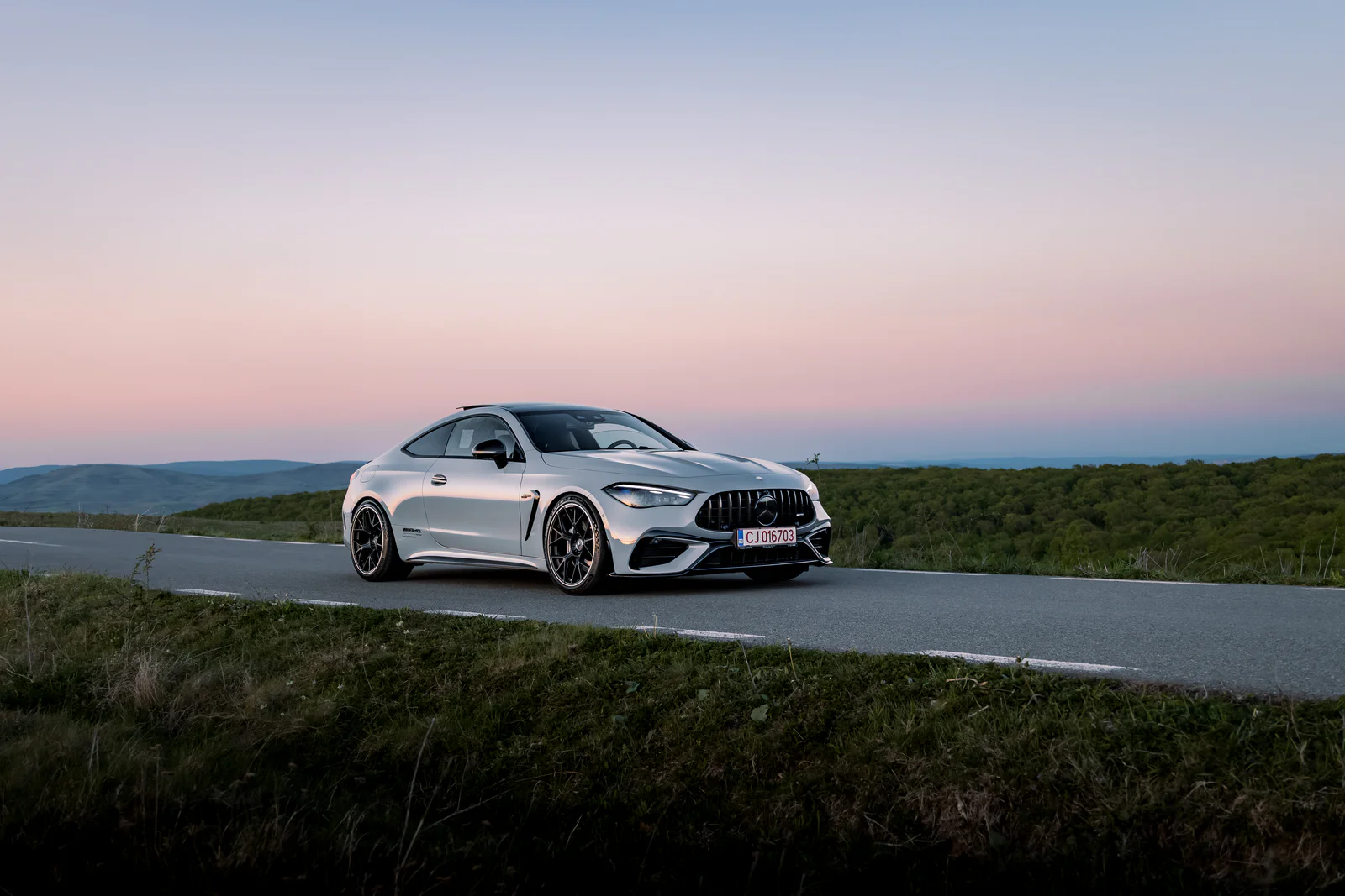 Wide front three-quarter view on a hillside road at dusk
