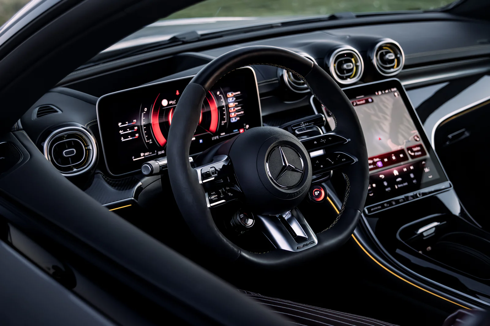 Wide cockpit view showing the AMG steering wheel, screens and circular vents